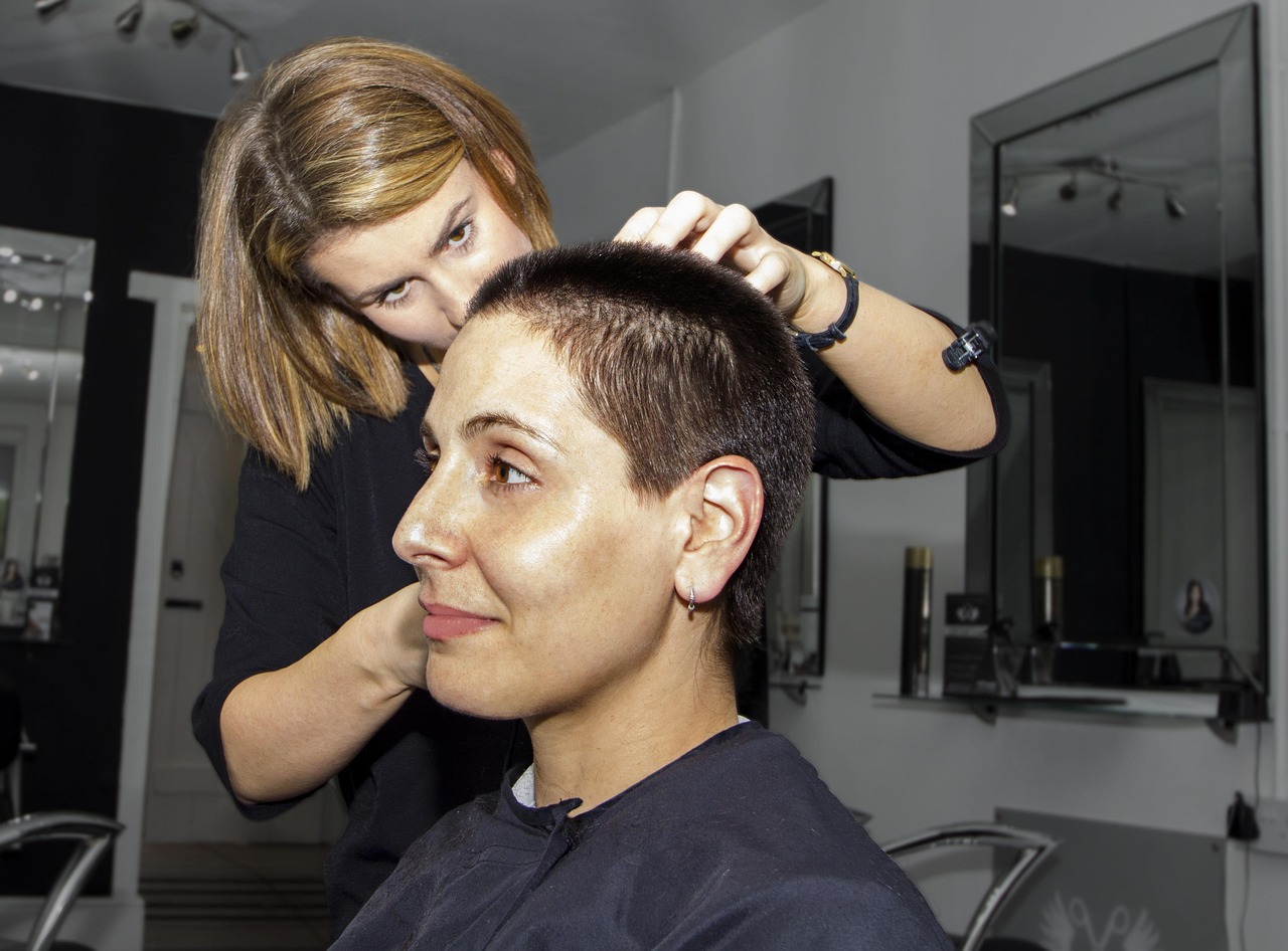 A woman stylist working on a seated client's short haircut in a bright salon